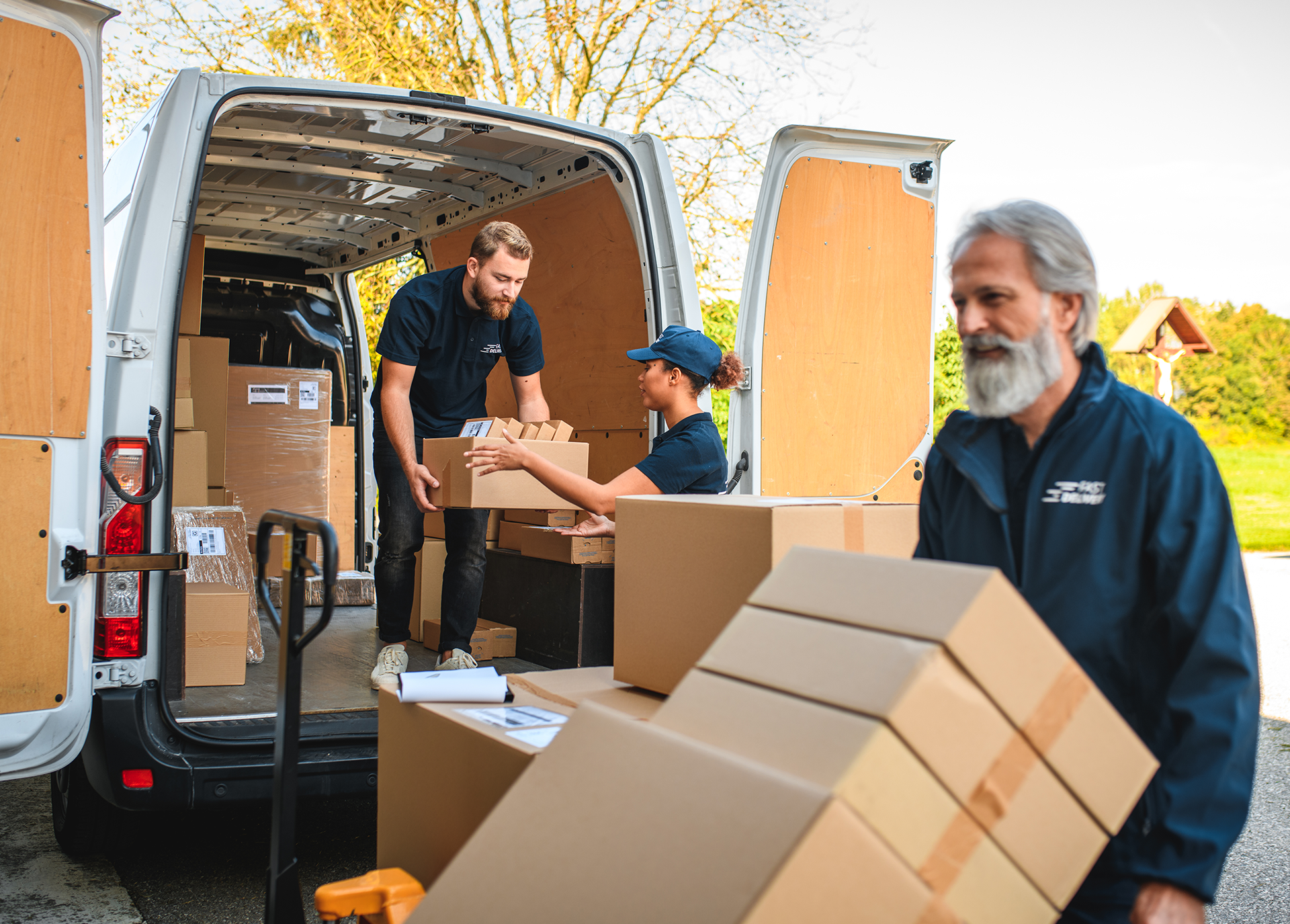 two people moving boxes into a truck, while one person moves boxes with a tool