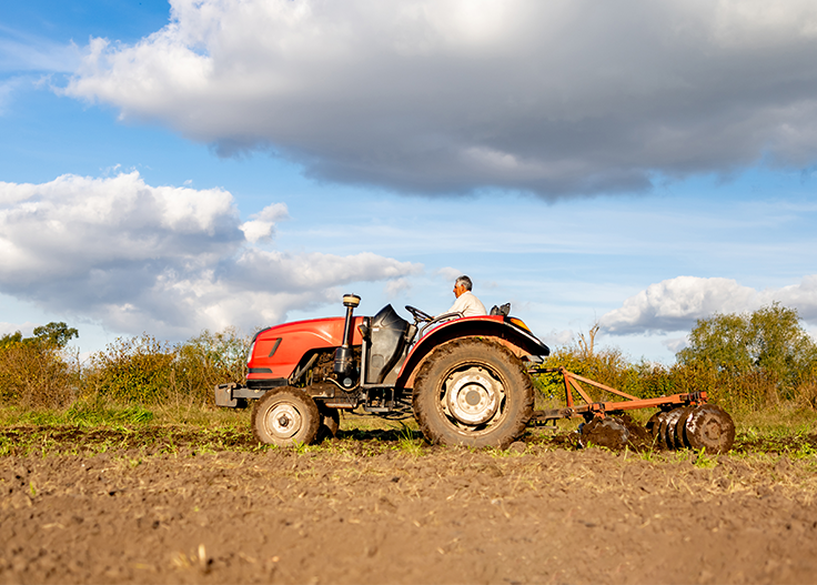 man driving a tractor on a farm field