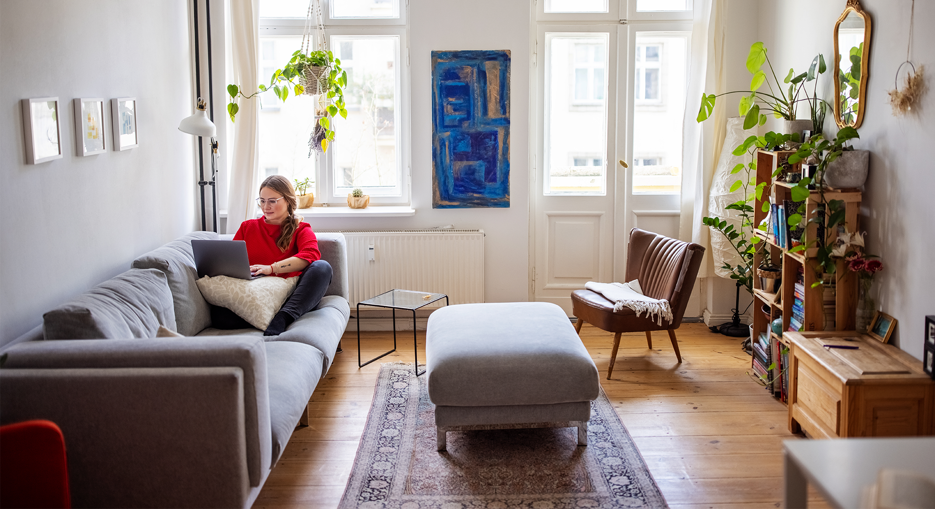 woman on a computer while laying on a couch in her condo